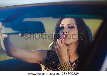 Young woman in convertible looking in mirror