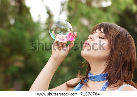 Attractive girl inflating soap bubbles outdoors