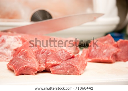 Slices of the meat on the board with knife on the kitchen
