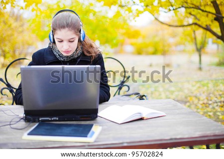 young attractive woman with headphones and laptop computer in park