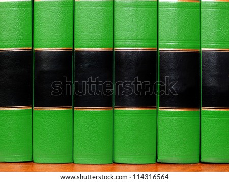 Row of old green leather books on a shelf with blank covers