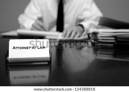 Attorney at Law sitting at desk holding pen with files with business card