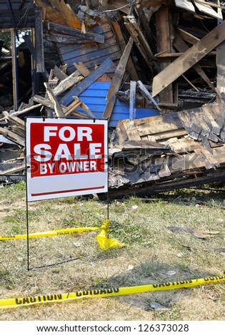 Home with fire damage and yellow caution tape and for sale sign