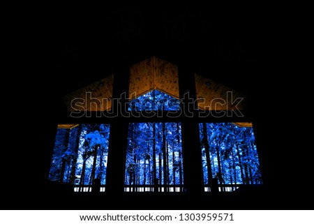 Cabin windows looking out into the dark at snow covered forest in winter