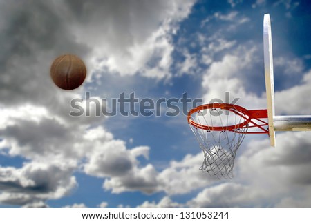Basketball shot on outdoor court with sky and clouds in background