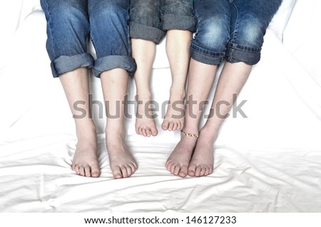 Family sitting with jeans rolled up sharing fun moment of happiness together bare feet