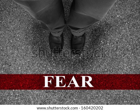 Businessman standing on asphalt starting line with word fear