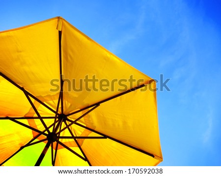 Yellow umbrella and blue sky symbolizing vacationing in summer