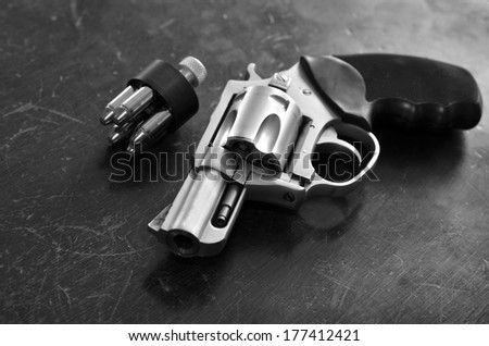 Closeup of powerful handgun with bullets on old wooden surface
