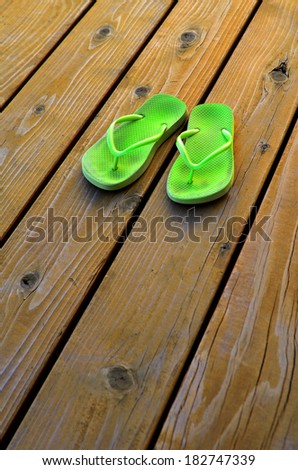 Detail of green flip flops for summer on old wooden deck