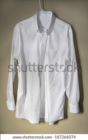 Detail of white dress shirt hanging on hanger with light