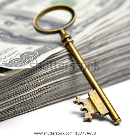 Old key laying on top of stack of cash money