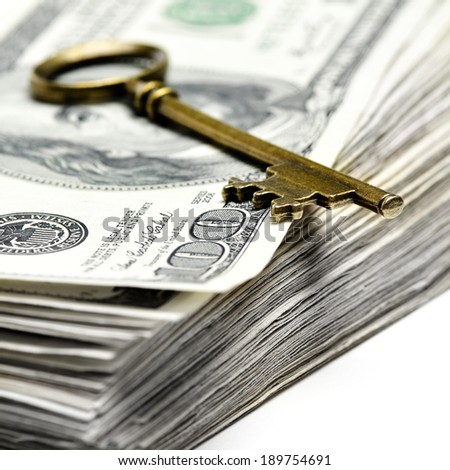 Old key laying on top of stack of cash money