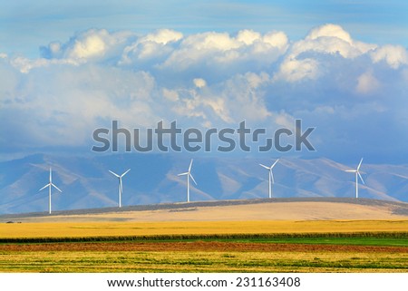 Detail of windmills on wind-farm wind farm with mountains and clouds