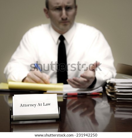 Attorney at Law sitting at desk holding pen with files