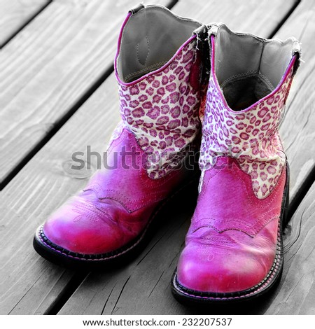 Detail of pink cowgirl cowboy boots on wood deck for a girl