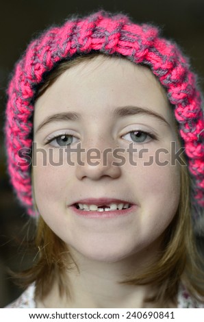 Little girl smiling portrait missing front tooth with winter hat