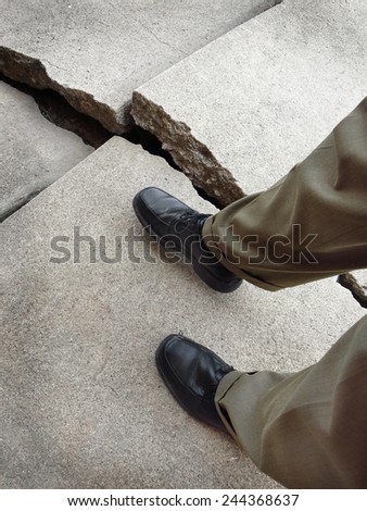 Man walking on broken dangerous cracked sidewalk
