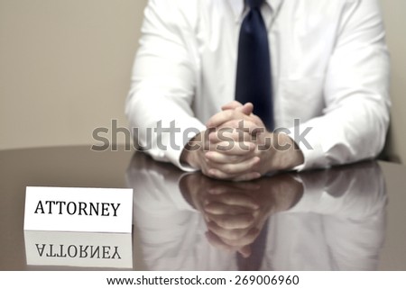 Attorney at Law sitting at desk holding pen with files with business card
