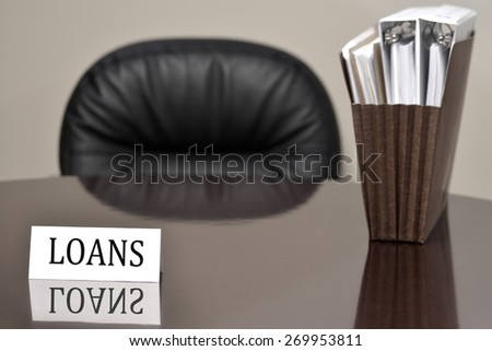 Business card for loans lending on desk with files and chair