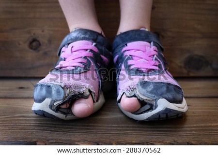 Detailed photo of shoes with holes in them and toes sticking out child kid young