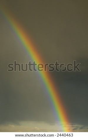 Colorful bright rainbow set against stormy sky