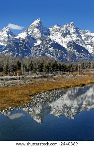 Detail of Grand Tetons Mountains with blue sky with reflection in river