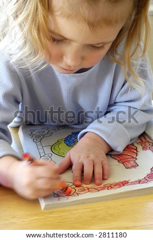 Little child coloring in coloring book with crayons