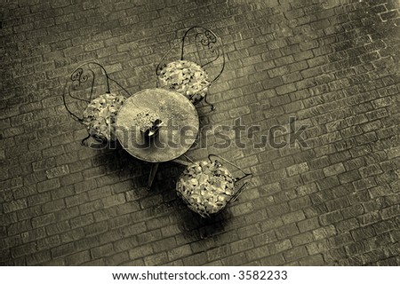 Sepia detail of table and chairs on cobblestone at an outdoor cafe