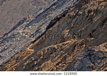 Several people climbing along rocky ridge on a trail