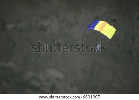 Person floating to the ground with a colorful parachute