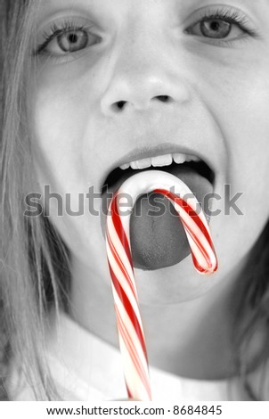 Closeup of young girl eating a candy cane