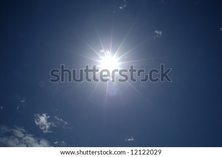 Blazing hot sun shining in blue sky with clouds