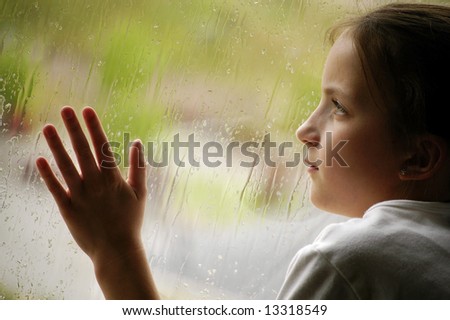 Girl looking out window on a rainy day