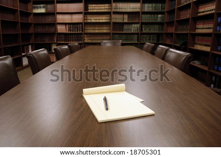 Conference room table with several leather chairs and shelves of books
