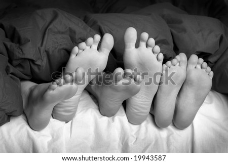 Several feet poking out of blankets on bed