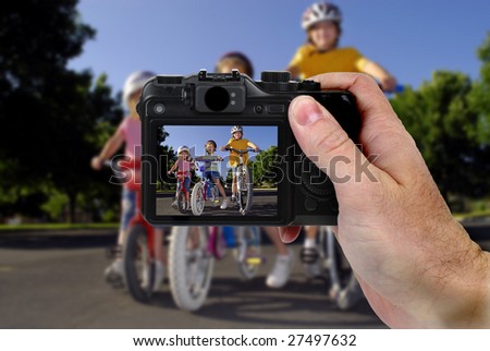 Hand holding camera taking a picture of little girls riding bikes