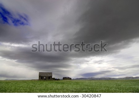 Old cabin in field with storm clouds in sky