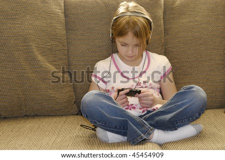 Little girl on couch listening to mp3 music with earphones