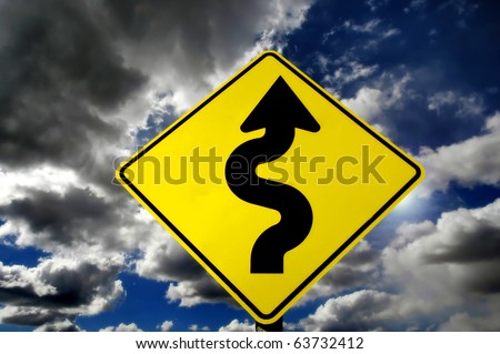 Yellow street sign with curves against stormy sky