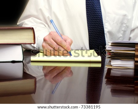 Business Man sitting at desk holding pen with files