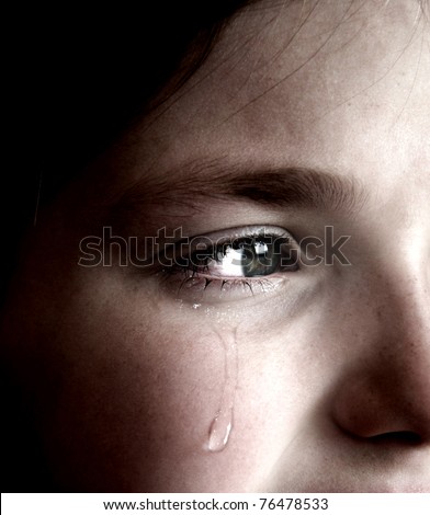 Closeup of girl crying with tear rolling down her cheek Closeup of girl crying with tear rolling down her cheek