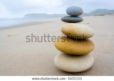 five stones accumulated in balance on the sand of a beach