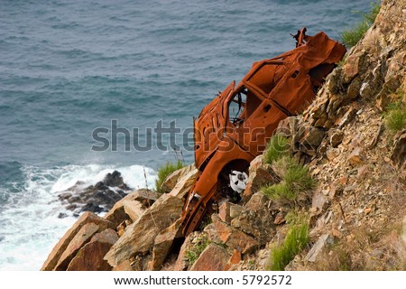 oxidized rest of a car left in a cliff