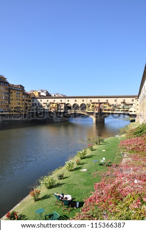 FLORENCE, ITALY - OCTOBER 22: unidentified couple relax on chairs in front of famous Ponte Vecchio in Florence on October 22, 2012. Florence is Unesco World Heritage Site since 1982.