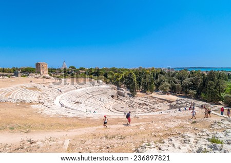 SYRACUSE, ITALY - AUGUST 18, 2014: tourists visit ancient Greek theater in Syracuse, Sicily, Italy. This monument is in the Unesco world heritage list.