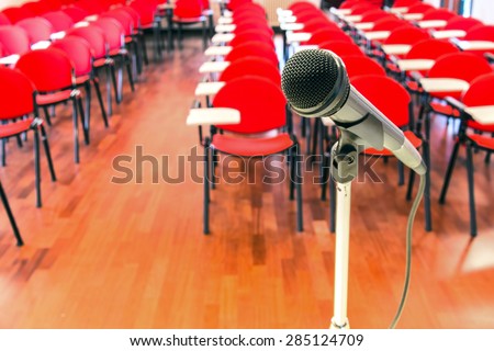 Close up of microphone in front of empty chairs in conference room