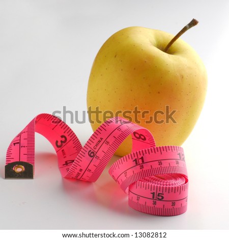 Curled pink measuring tape and apple on white background