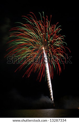 An explosion of red and green fireworks in the dark night sky