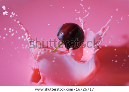 An extremely close view of a cherry splashing into pink liquid